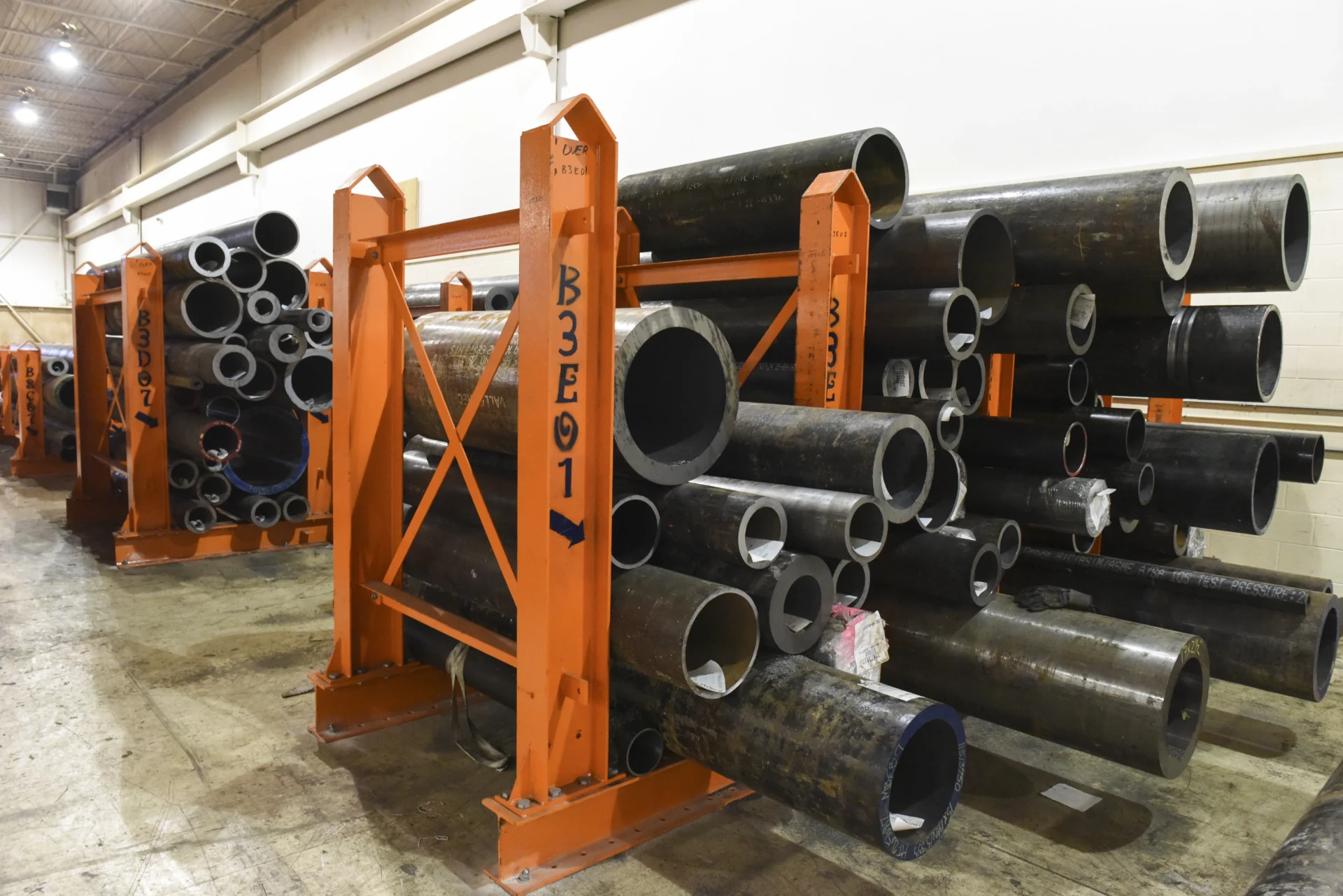 Dexco floor stanchion racks storing steel pipe and tube in an indoor distribution facility